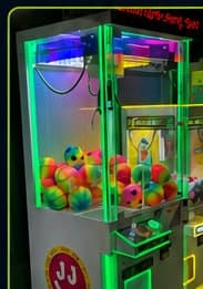 Neon-lit crane machine stocked with plush prizes