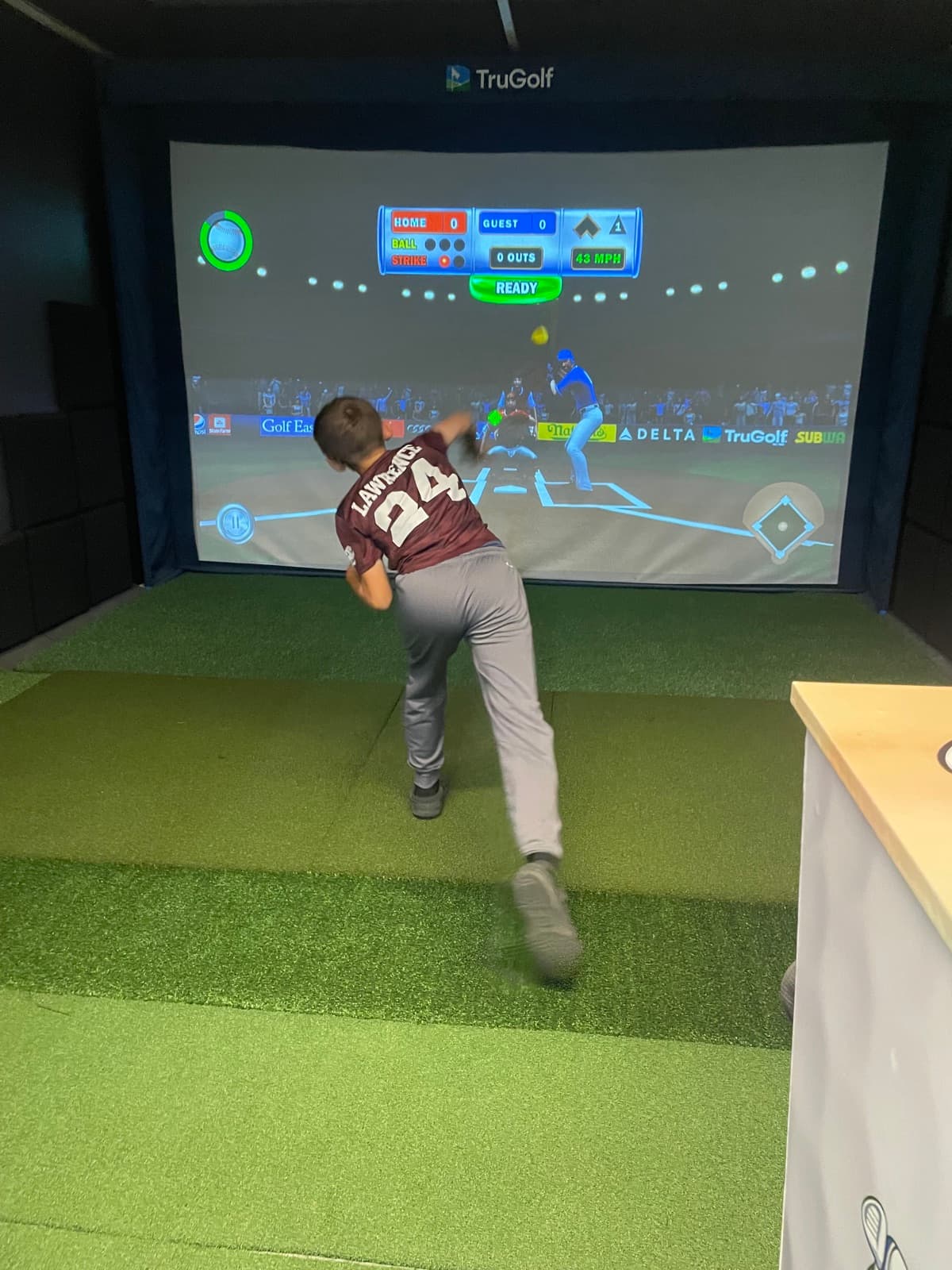 A young player swinging at a pitch in the baseball simulator game